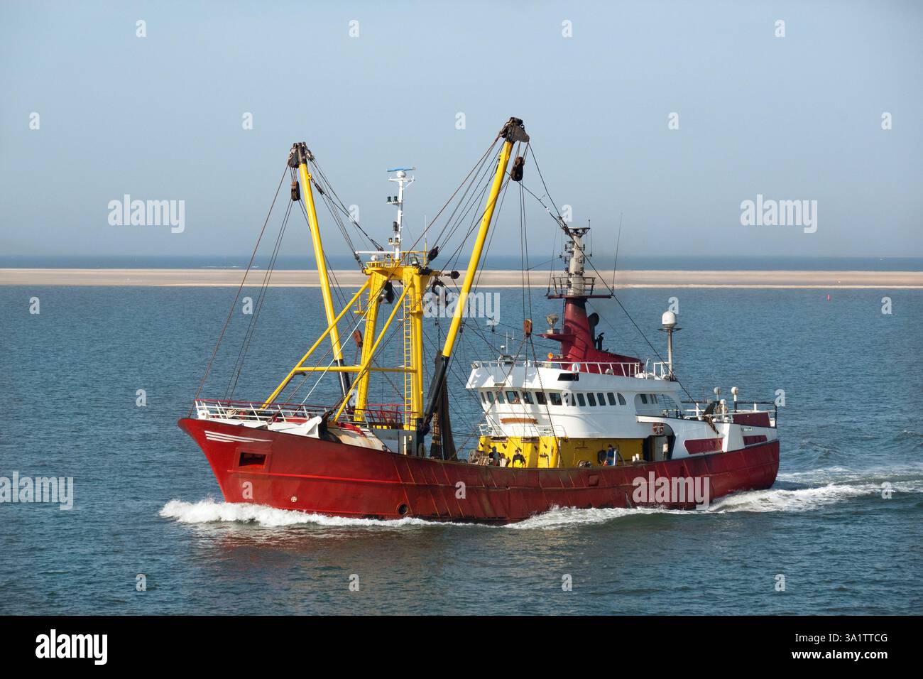 Bateau de pêche rouge et jaune en mer, en arrière-plan un banc de sable Banque D'Images