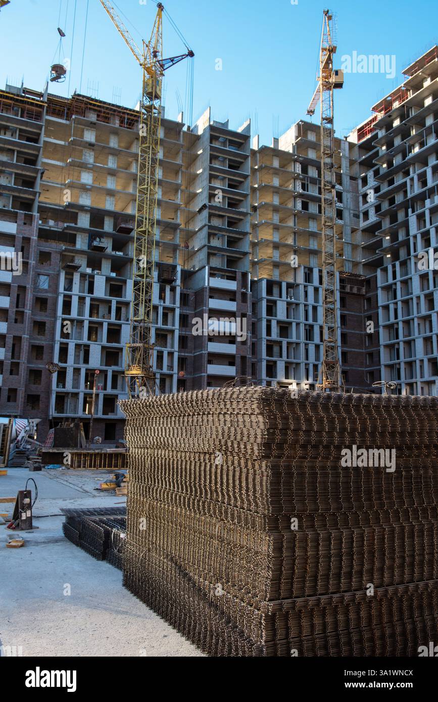 Construction en cours d'appartements modernes de grande hauteur avec grues, renforts en acier et structures inachevées. Banque D'Images