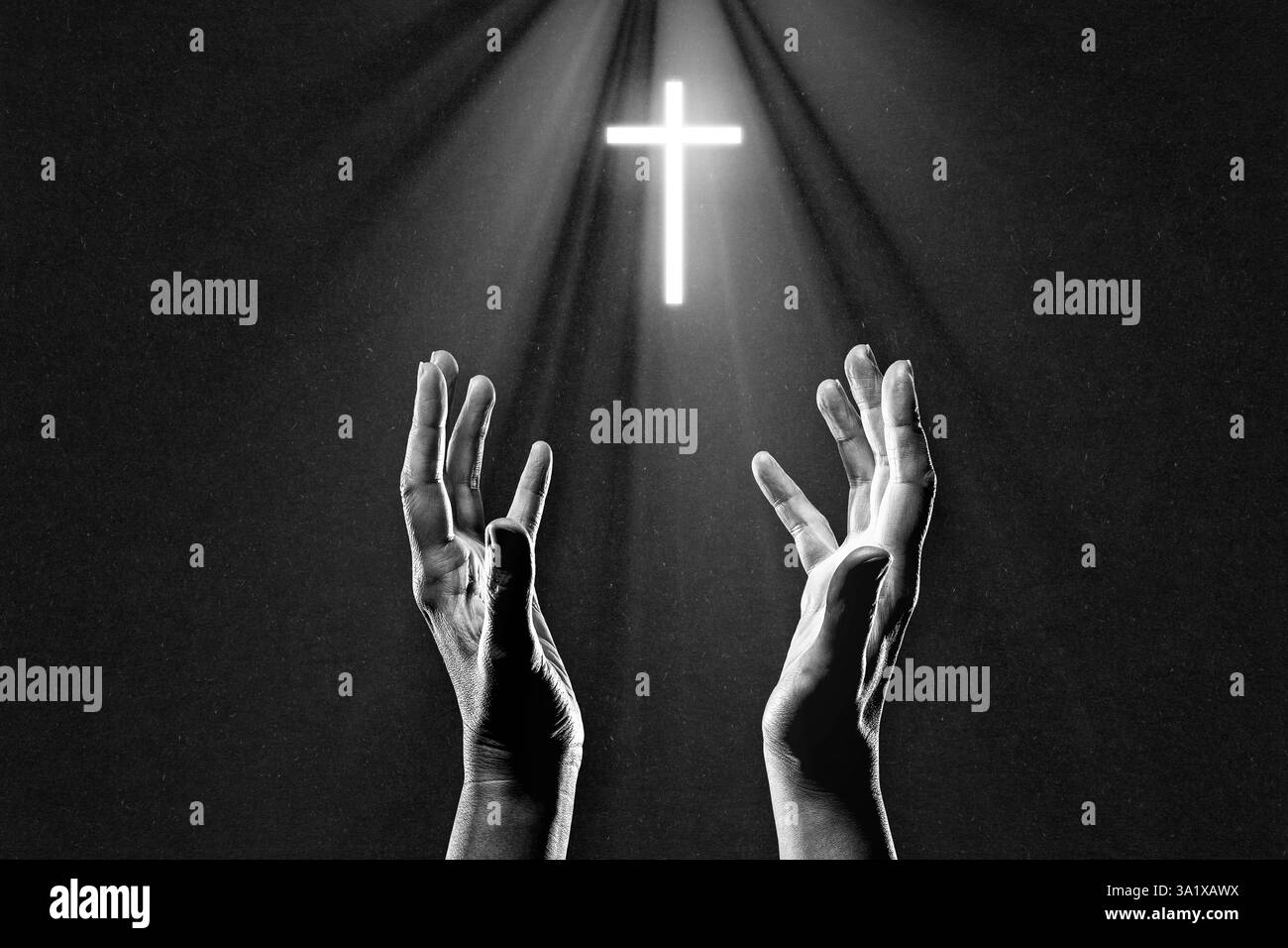 Main priant atteignant la Croix chrétienne illuminée en noir et blanc sur fond de papier texturé, espace de copie Banque D'Images