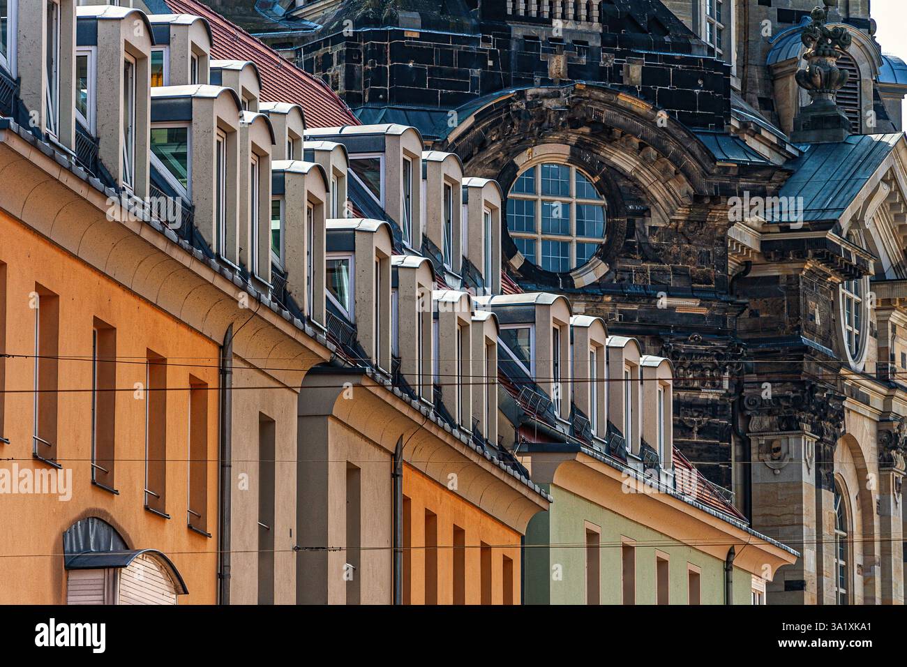 Une rangée de lucarnes colorées contraste avec la pierre sombre de la Frauenkirche à Dresde, en Allemagne, créant une juxtaposition architecturale intéressante. Banque D'Images