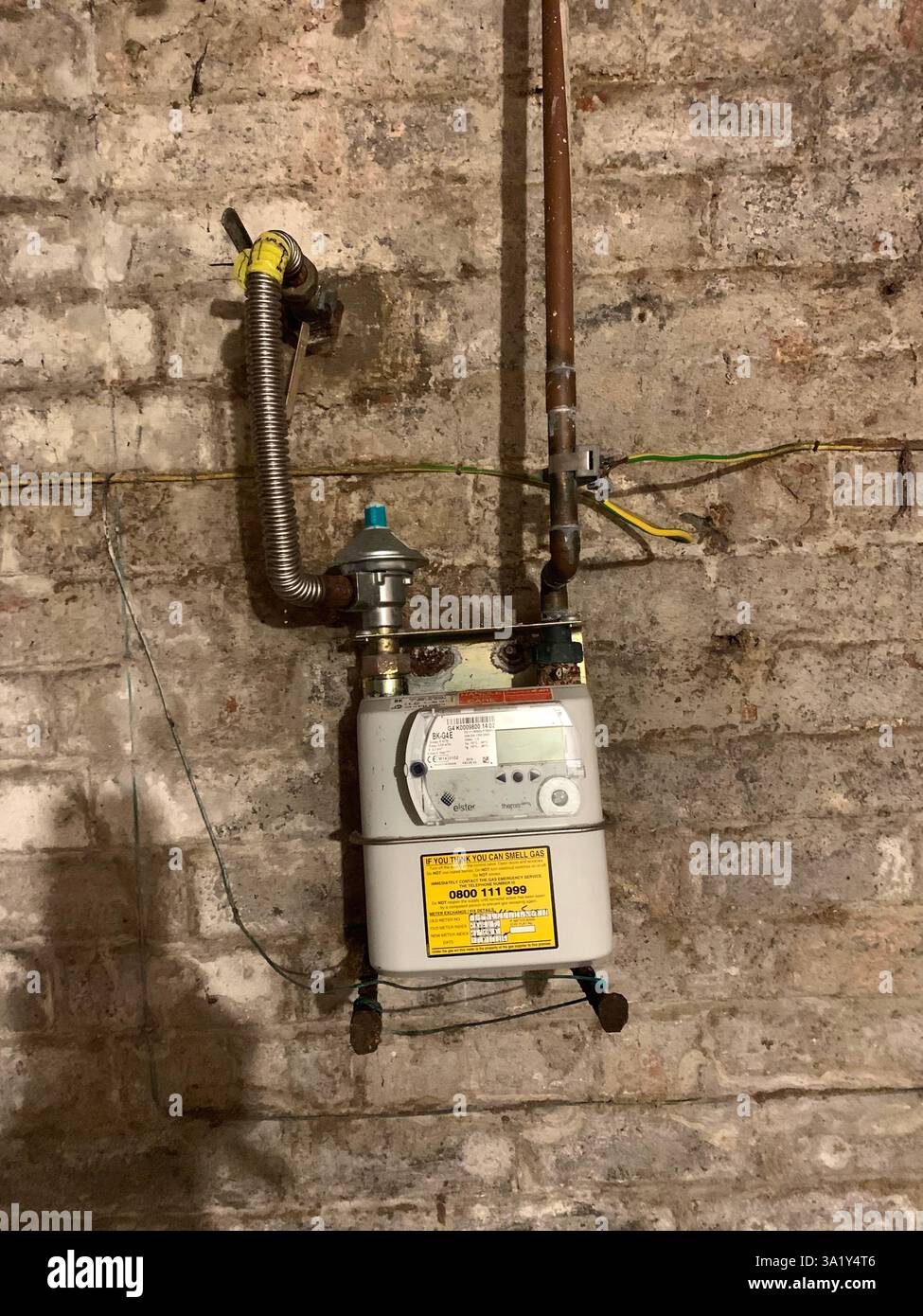Compteur de gaz dans une cave Northampton Angleterre Royaume-Uni style britannique vieux style tuyau de mur monté sur un mur sale tuyauterie vieillie briques briques ombre de cadran - Image de stock capturée avec un smartphone