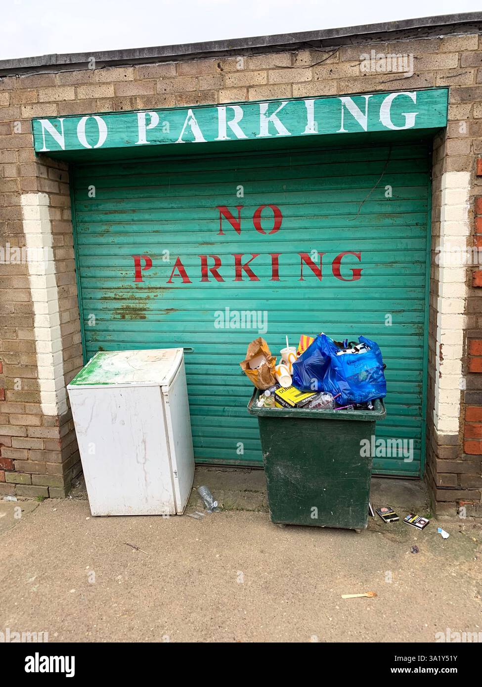 Pas de porte de garage vert signe peint pancartes poubelles collecte de déchets dans la rue à l'extérieur mur météo briques de briques de look désordonné place - Image de stock capturée avec un smartphone