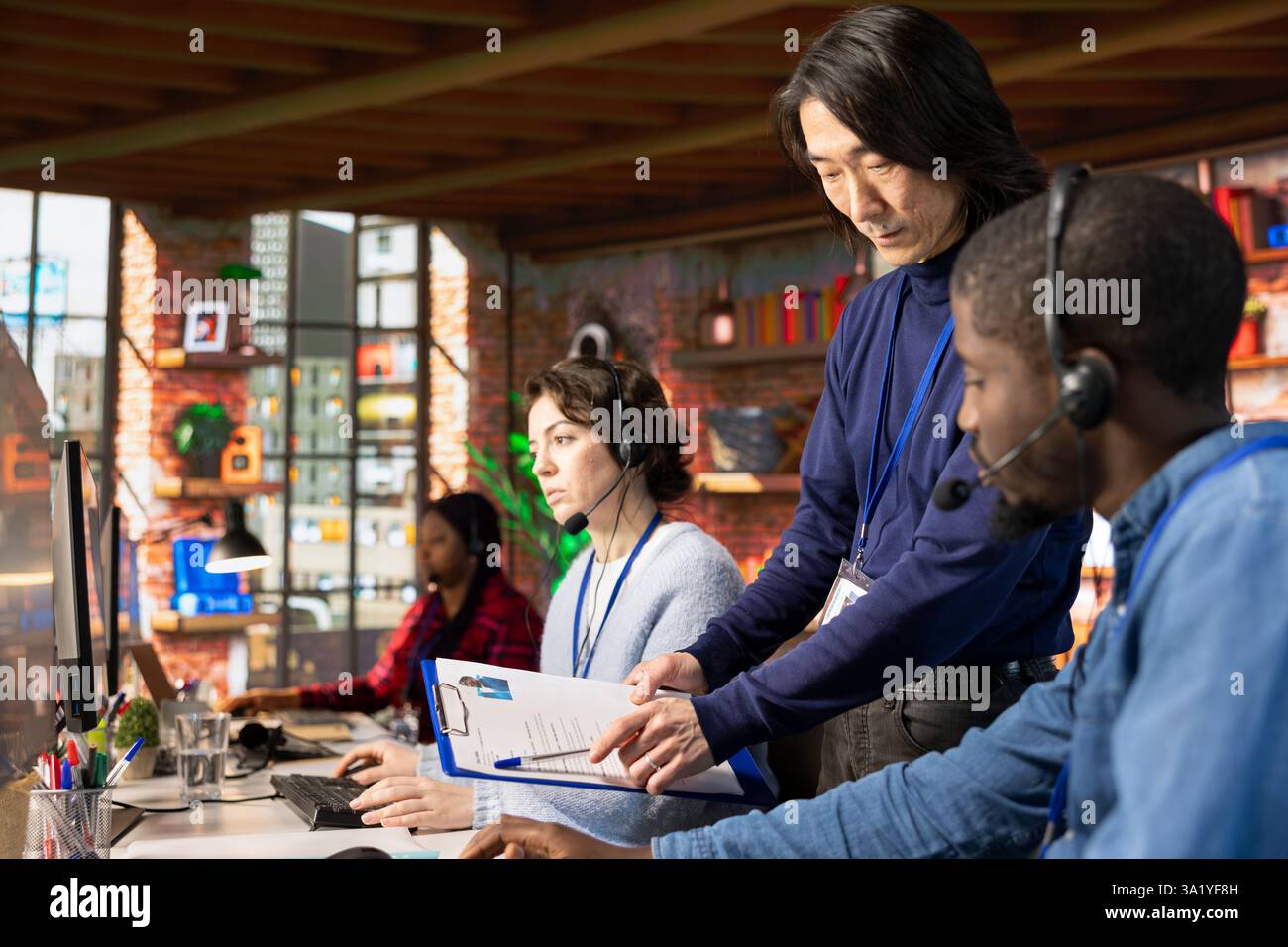 Le responsable senior du centre d'appels passe en revue le dossier de description du poste avec l'employé au bureau du PC. Spécialiste asiatique de l'intégration du support à la clientèle expliquant les tâches au stagiaire qui s'adapte à son emploi Banque D'Images