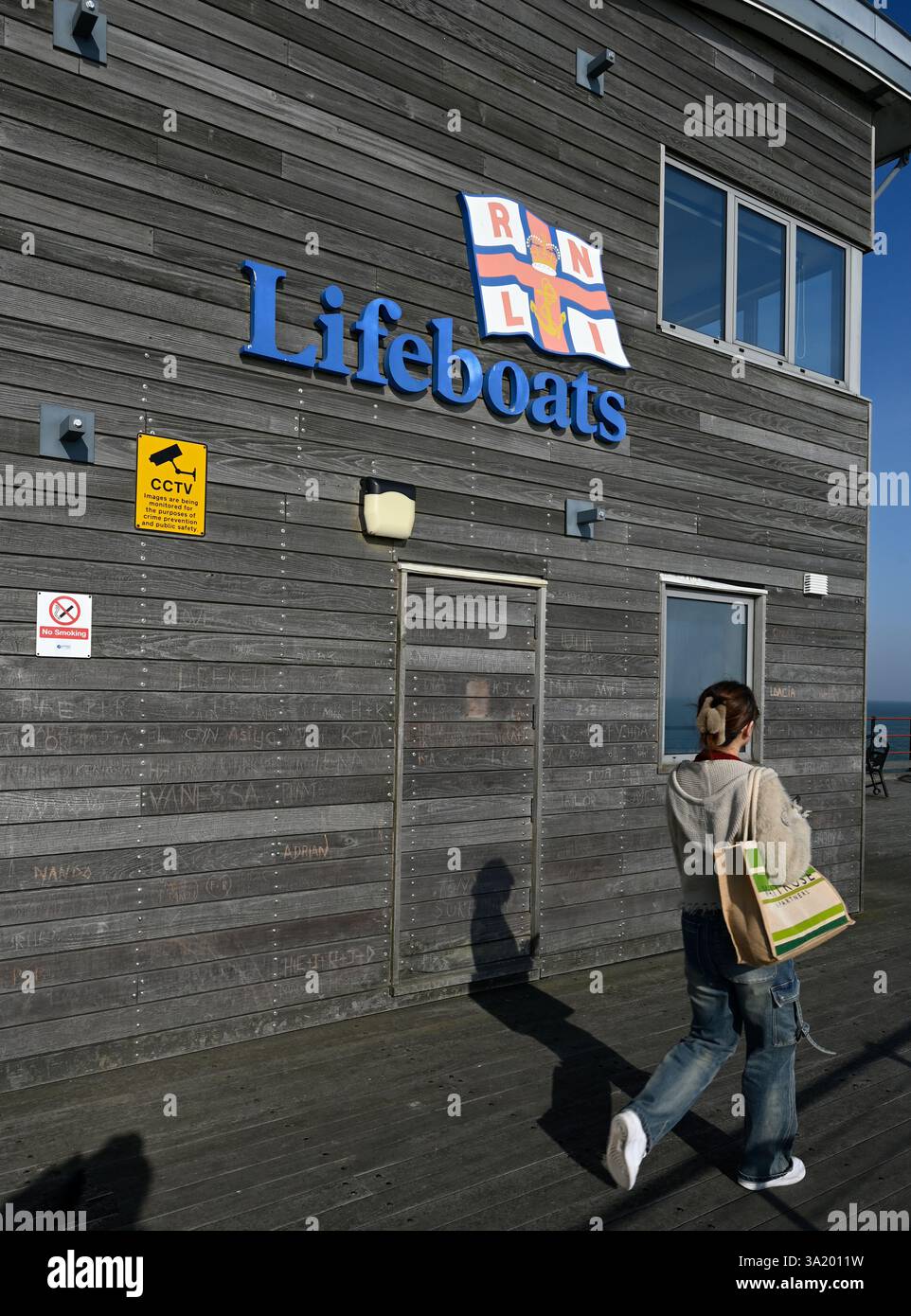 Une dame se promène par les bateaux de sauvetage construisant sur le pont de soleil à la Pier Head sur la plus longue jetée de plaisance du monde, Southend on Sea, City of Southend UK. Banque D'Images