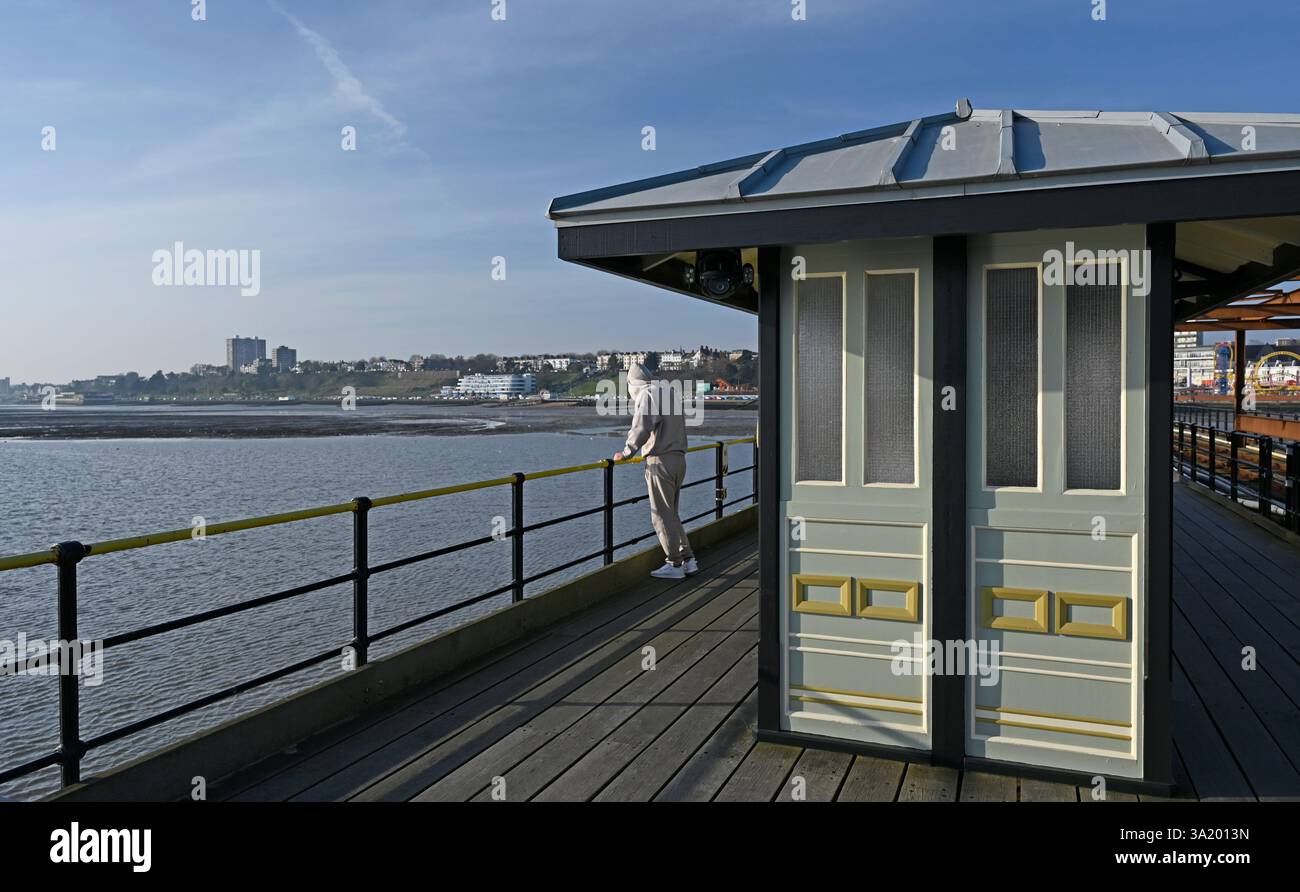 Un homme regarde vers la mer à côté de l'un des quatre abris positionnés sur la plus longue jetée de plaisance du monde à Southend on Sea, ville de Southend. ROYAUME-UNI. Banque D'Images
