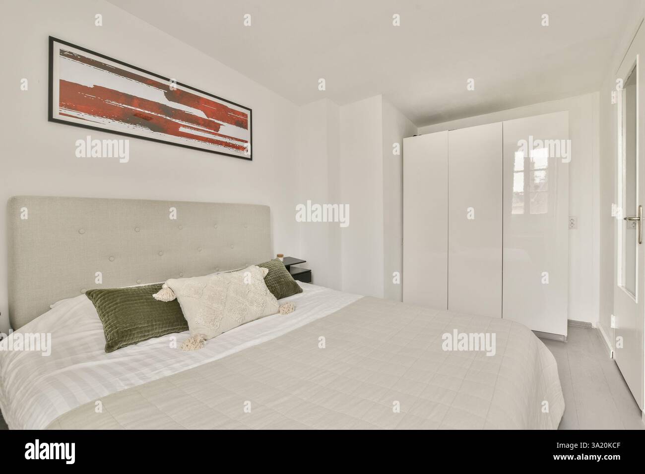 Une chambre contemporaine avec une élégante armoire blanche, un lit soigné et un décor minimaliste qui met l'accent sur la simplicité et l'élégance. Banque D'Images