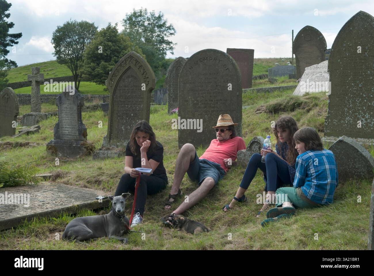 Groupe familial et chien de compagnie, assis dans un cimetière d'église le cimetière à St Stephens Church - Forest Chapel Macclesfield Forest, Macclesfield, Cheshire, Angleterre 13 août 2017 2010s UK HOMER SYKES Banque D'Images