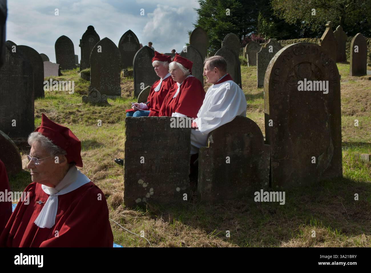 Église St Stephens - Chapelle forestière Rushbear service d'église en plein air. Les membres de la chorale vêtus de rouge sont assis dans le cimetière parmi les pierres tombales lors de la célébration annuelle du Rush Bearing. Macclesfield Forest, Macclesfield, Cheshire, Angleterre 13 août 2017 2010s UK HOMER SYKES Banque D'Images