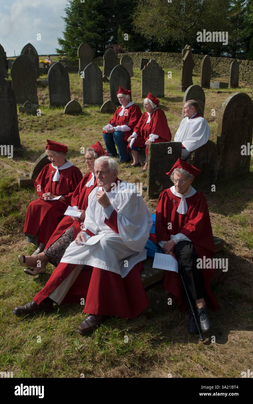 Église St Stephens - Chapelle forestière Rushbear service d'église en plein air. Les membres de la chorale vêtus de rouge sont assis dans le cimetière parmi les pierres tombales lors de la célébration annuelle du Rush Bearing. Macclesfield Forest, Macclesfield, Cheshire, Angleterre 13 août 2017 2010s UK HOMER SYKES Banque D'Images