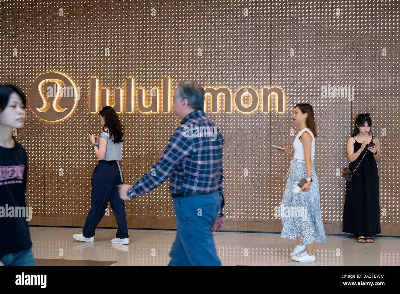 Les acheteurs passent devant le magasin de vêtements de sport canadien, Lululemon, à Hong Kong. Banque D'Images