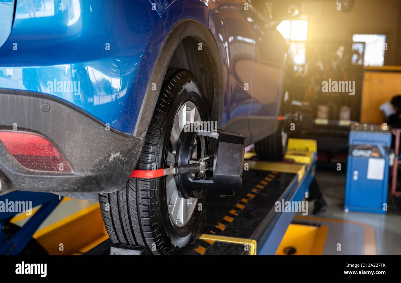 L'équipement de réglage de la géométrie des roues accroche le pneu de la roue de voiture dans l'atelier de réparation automobile. Alignement automatique des roues dans l'atelier de la station-service. Equilibre des roues de la voiture. Banque D'Images
