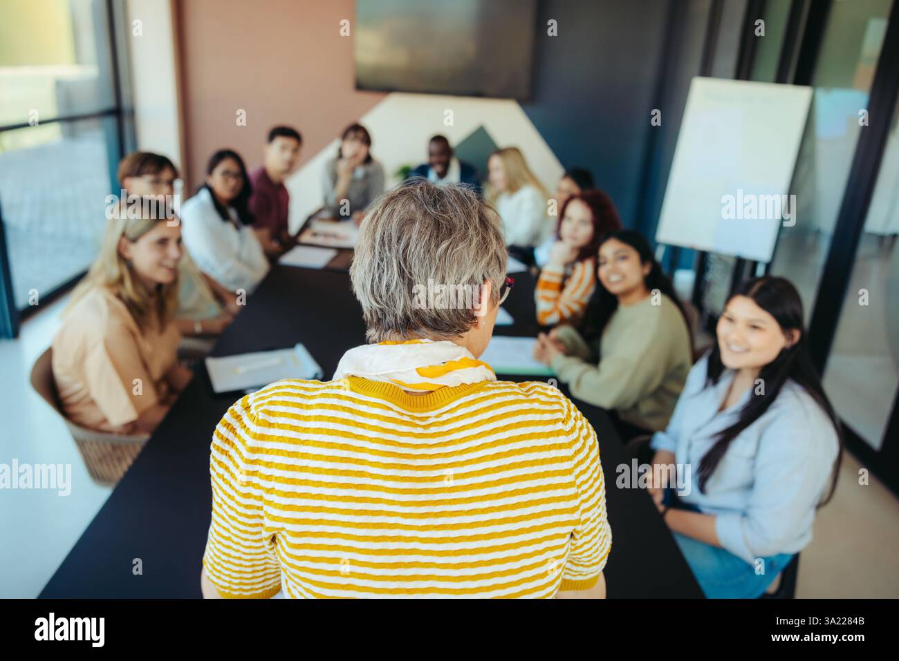 Une petite classe avec des étudiants divers engagés dans l'apprentissage. Un enseignant mène la discussion dans un environnement lumineux et moderne, en promouvant l'éducation et inter Banque D'Images