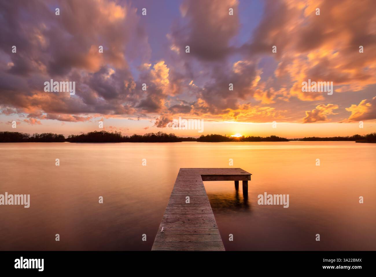 Le soleil se couche au Paterswoldse Meer à Groningen sur une belle soirée avec des couleurs vibrantes dans le ciel et un reflet sur l'eau Banque D'Images