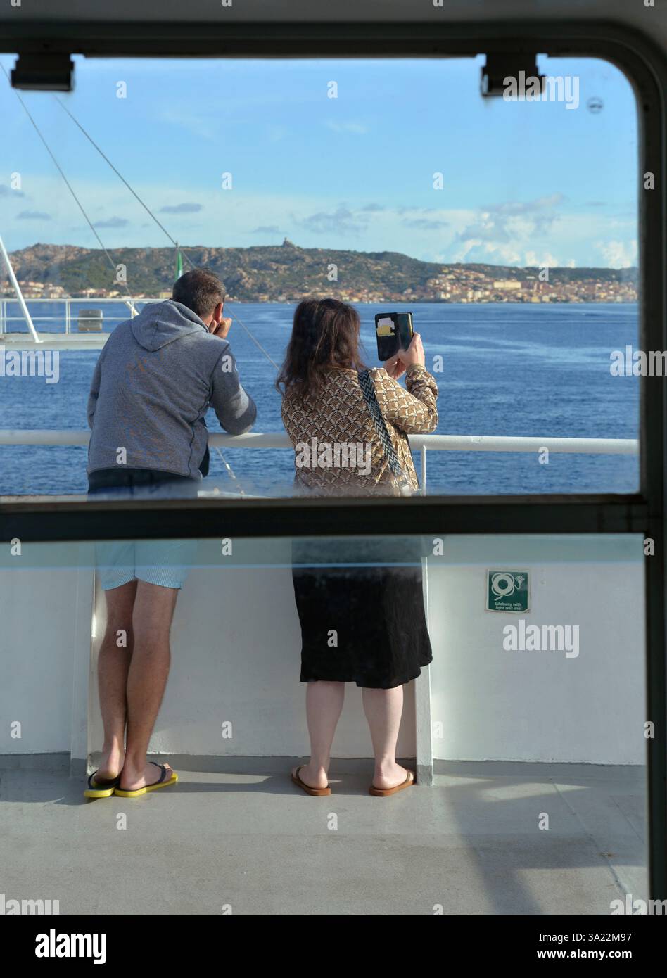 Couple de passagers sur le pont extérieur vu à travers la fenêtre d'un ferry lors d'une excursion d'une journée de Palau à l'île de la Maddalena, Sardaigne, Italie Banque D'Images