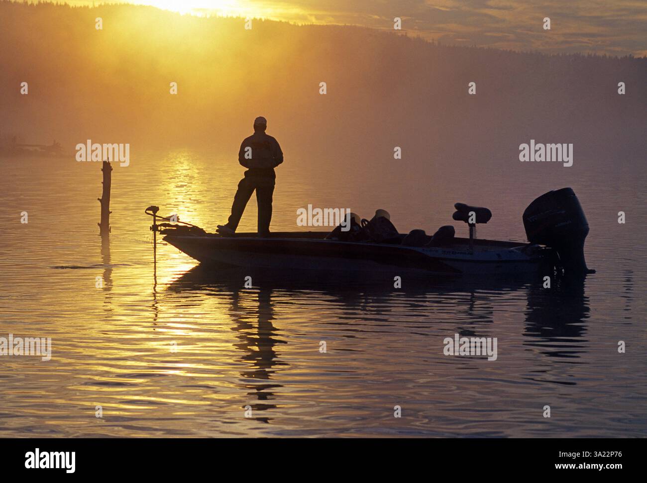 Un pêcheur de bar à grande bouche jette le bar à l'aube par un matin d'été brumeux au réservoir de Crane Prairie dans les Cascade Mountains du centre de l'Oregon. Banque D'Images