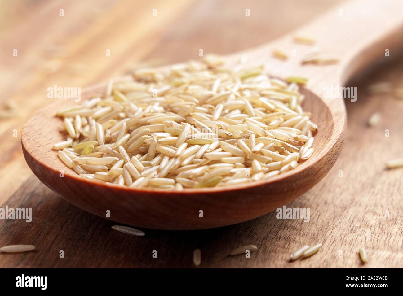 Riz basmati à grains longs non transformé dans une cuillère en bois. Aliments diététiques. Banque D'Images