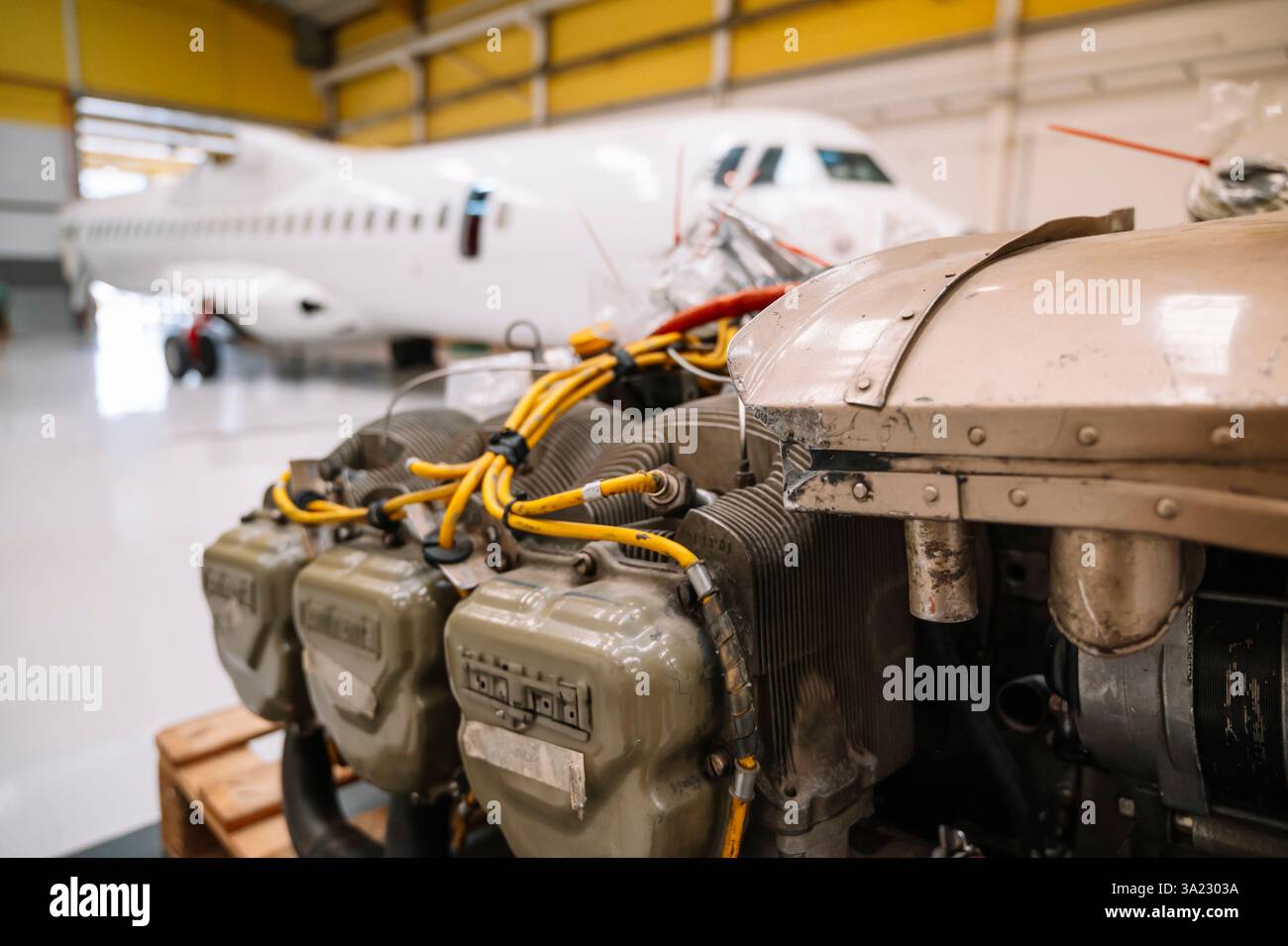 Un moteur d'avion est représenté dans un hangar avec un avion blanc en arrière-plan Banque D'Images