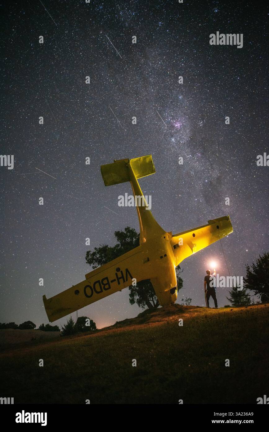 personne avec la lumière debout à côté de l'avion jaune la nuit et étoiles filantes avec Banque D'Images