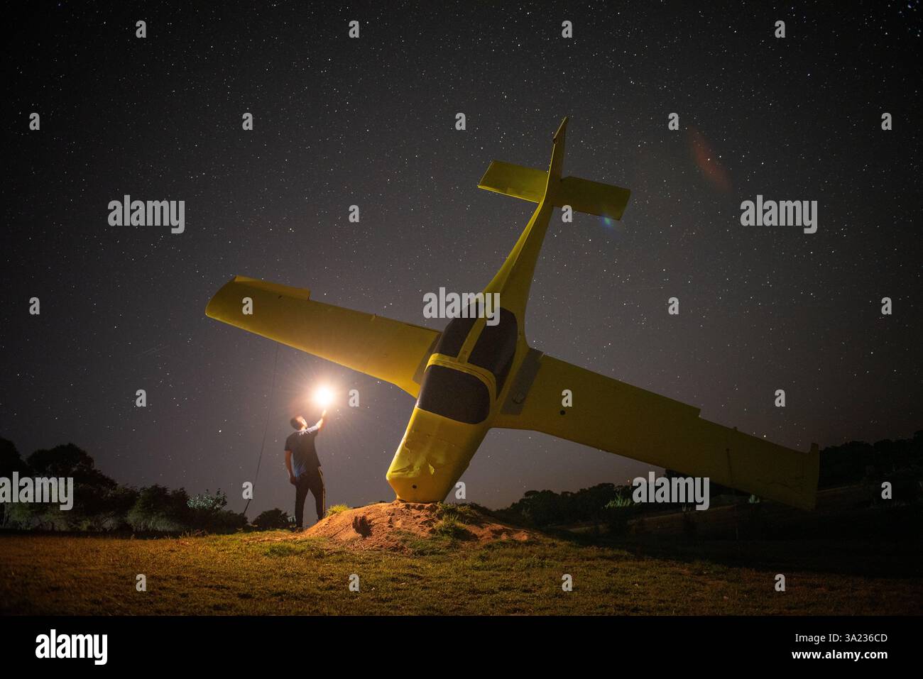 personne avec la lumière debout à côté de l'avion jaune la nuit et étoiles filantes avec Banque D'Images
