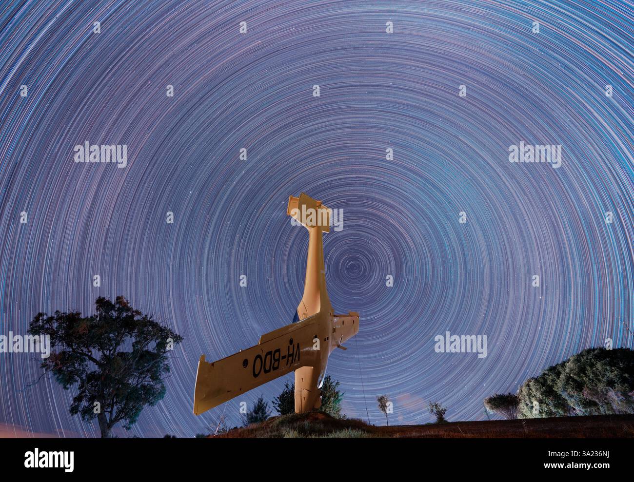 traînées d'étoiles colorées avec avion jaune contre ciel nocturne Banque D'Images