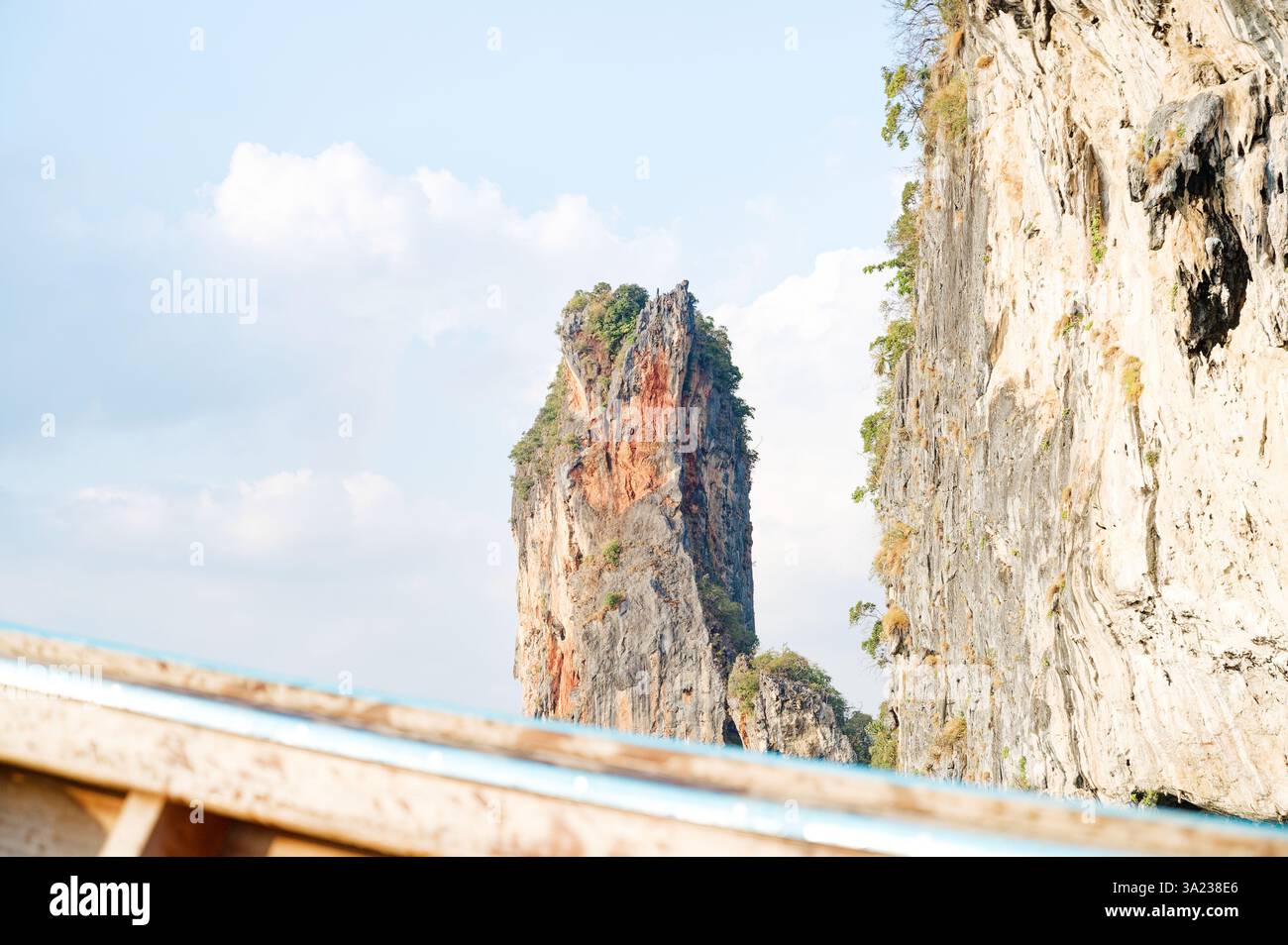 D'imposantes falaises de calcaire s'élèvent de façon spectaculaire de la mer, vues du bord d'un bateau à longue queue traditionnel Banque D'Images