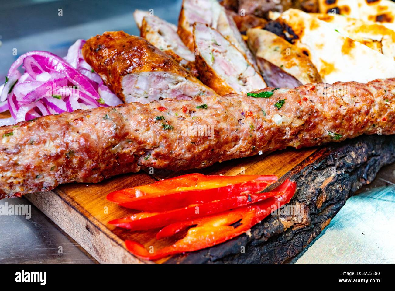 Un délicieux plat présente des saucisses grillées, des viandes tendres, des oignons tranchés et des poivrons rouges. Les couleurs vibrantes et la présentation appétissante invitent di Banque D'Images