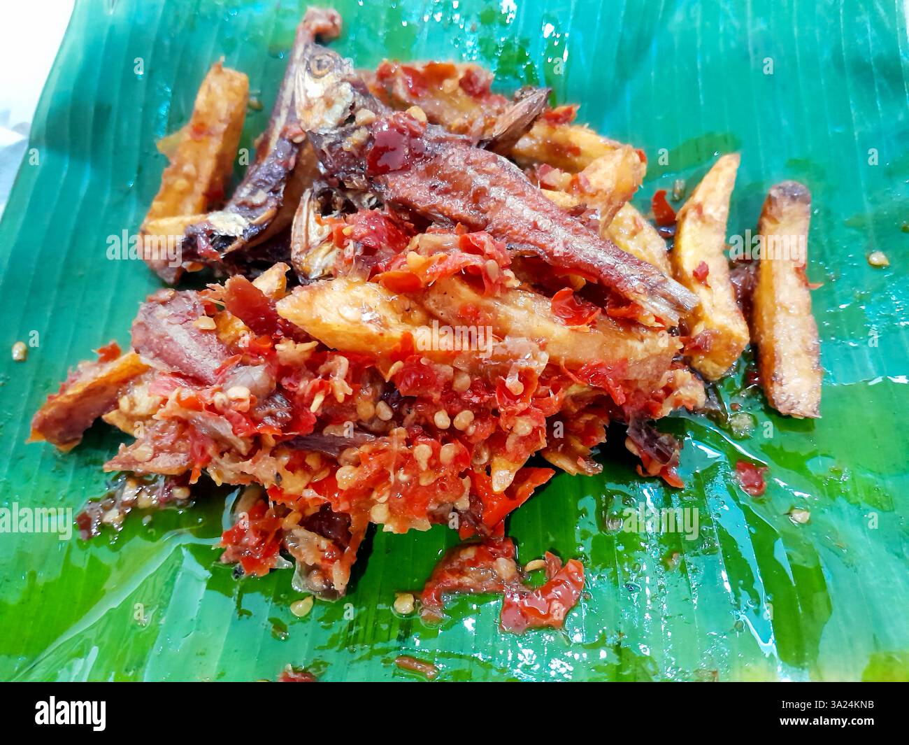 Minangkabau Teri Kentang balado indonésien ou anchois séchés frits et pommes de terre au piment rouge sambal balado, servis sur une feuille de banane. Banque D'Images