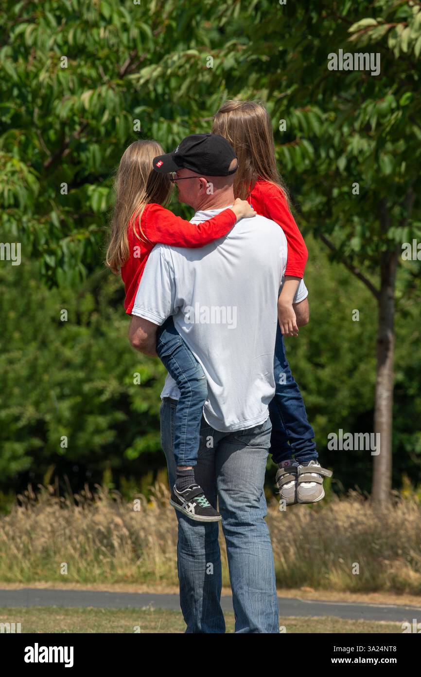 père portant deux enfants Banque D'Images