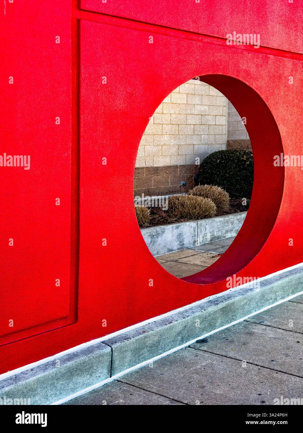 Mur rouge percé d'un trou à l'extérieur d'un magasin Target. Banque D'Images