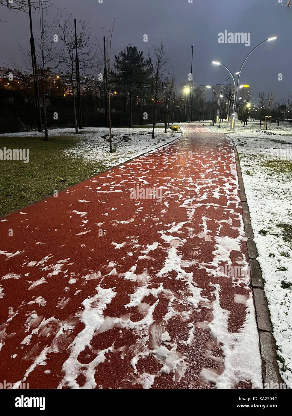 Effet de course à pied sur une piste de sport en plein air dans la nuit neigeuse. Banque D'Images