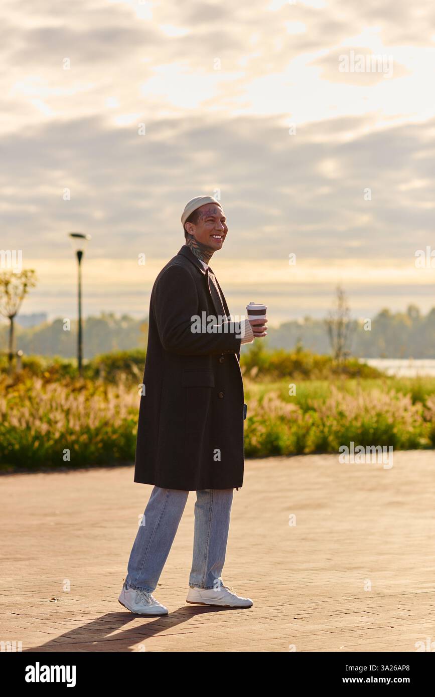 Homme confiant tenant le café, modelant la mode moderne dans un cadre paisible. Banque D'Images