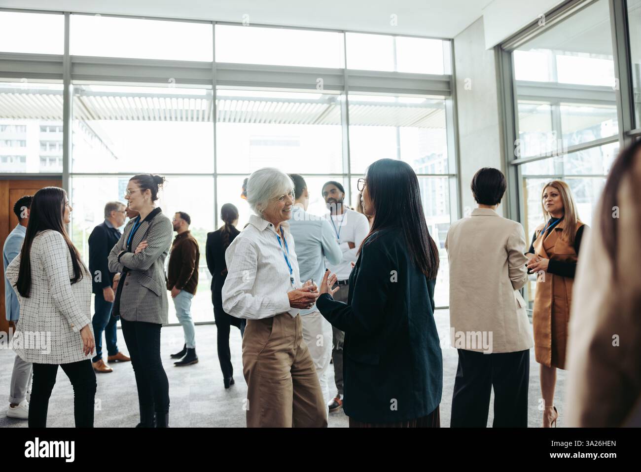 Groupe diversifié de professionnels réseautant, s'engageant dans des conversations et établissant des relations d'affaires lors d'un événement d'entreprise. Banque D'Images