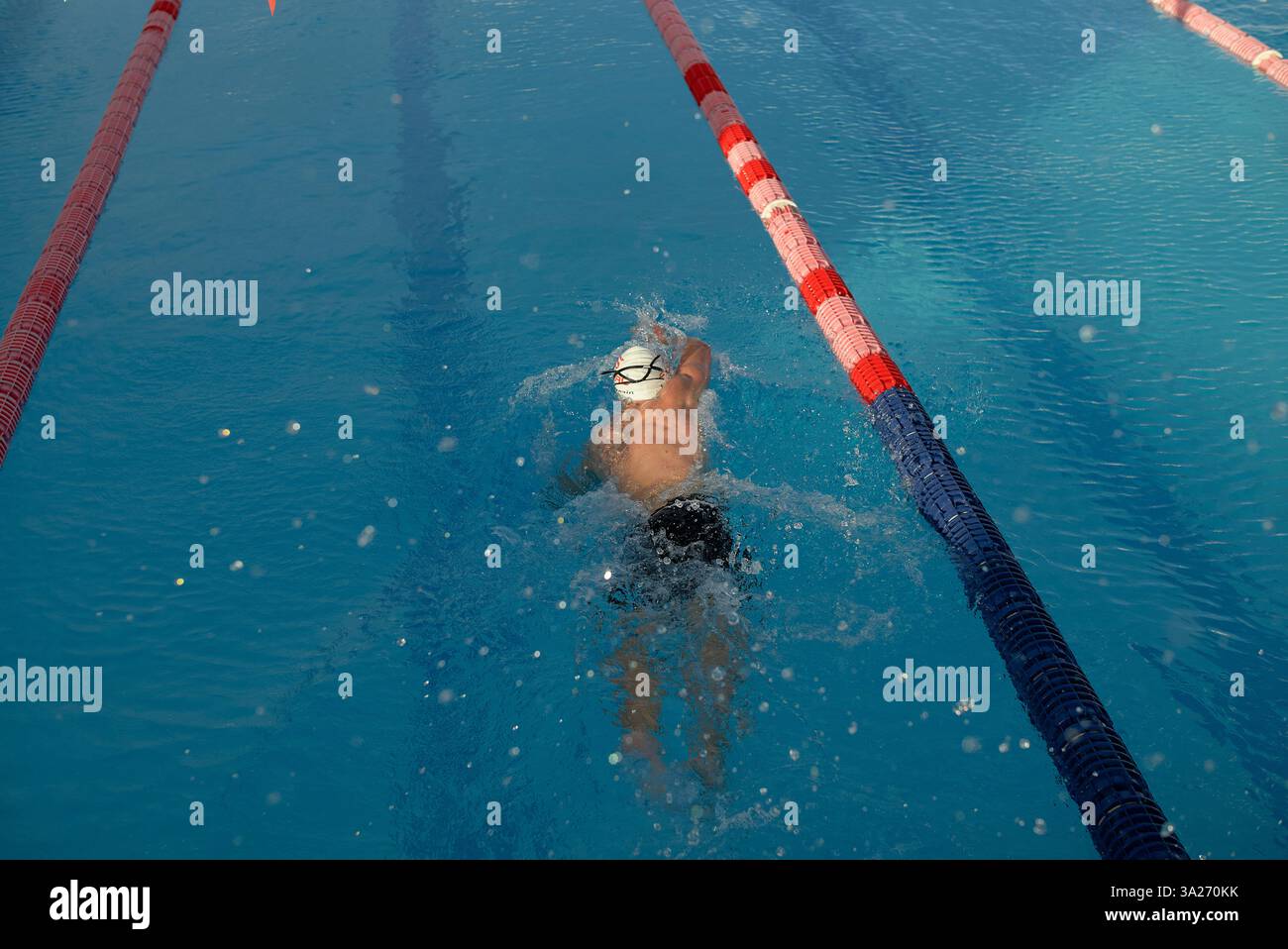 Nageur de triathlon en action dans une ruelle d'une piscine extérieure à l'eau bleue limpide. Banque D'Images
