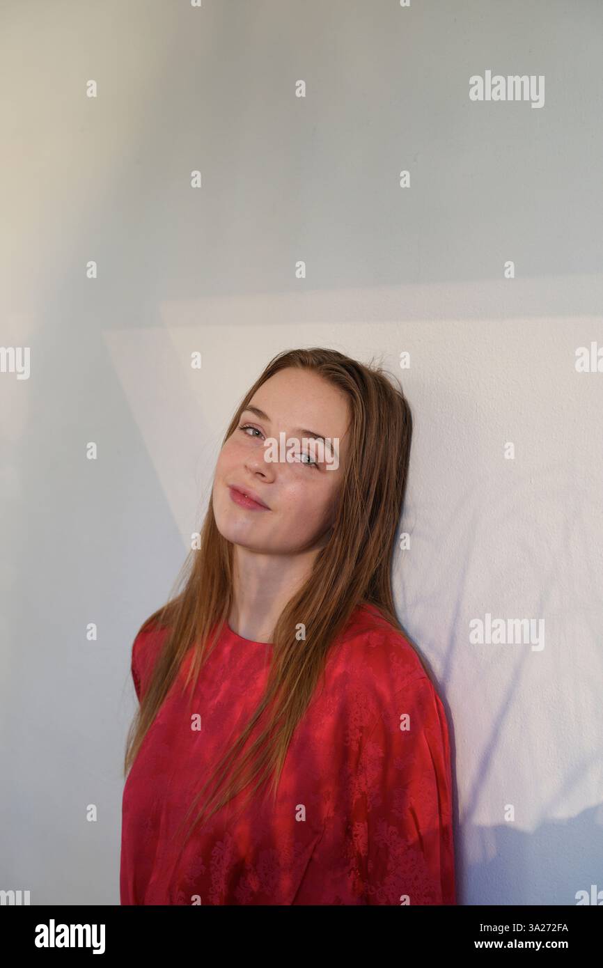 Jeune femme dans un haut rouge posant avec un doux sourire sur un fond silencieux. Miami, Floride, États-Unis Banque D'Images