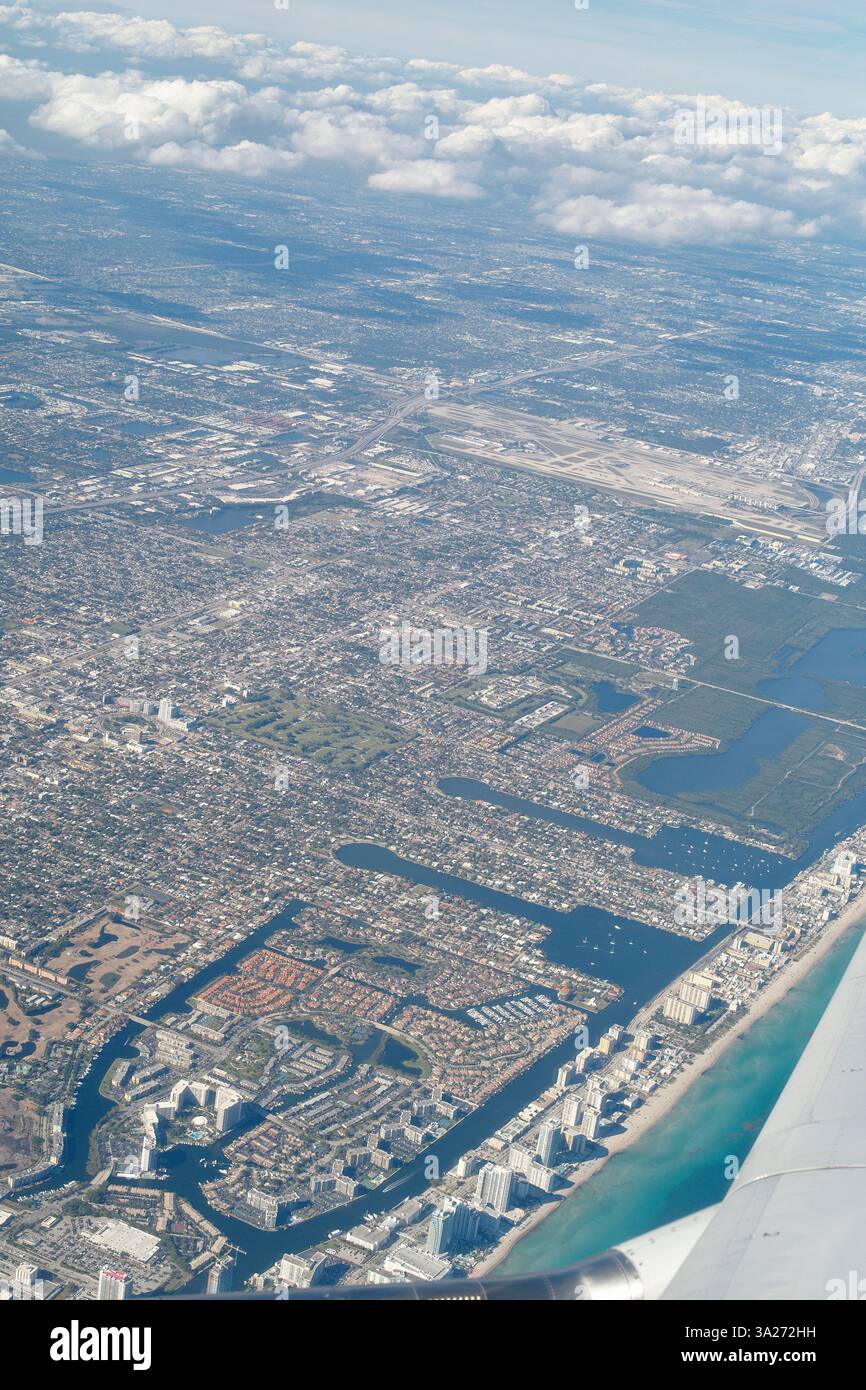 Vue aérienne d'un vaste paysage urbain avec des nuages dispersés et un littoral visible. Miami, Floride, États-Unis Banque D'Images
