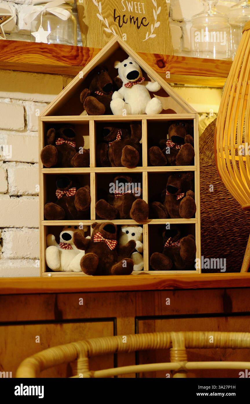 Un intérieur confortable de style rustique avec une étagère en bois en forme de maison remplie d'ours en peluche en peluche. L'éclairage chaleureux et le décor vintage créent un charmin Banque D'Images