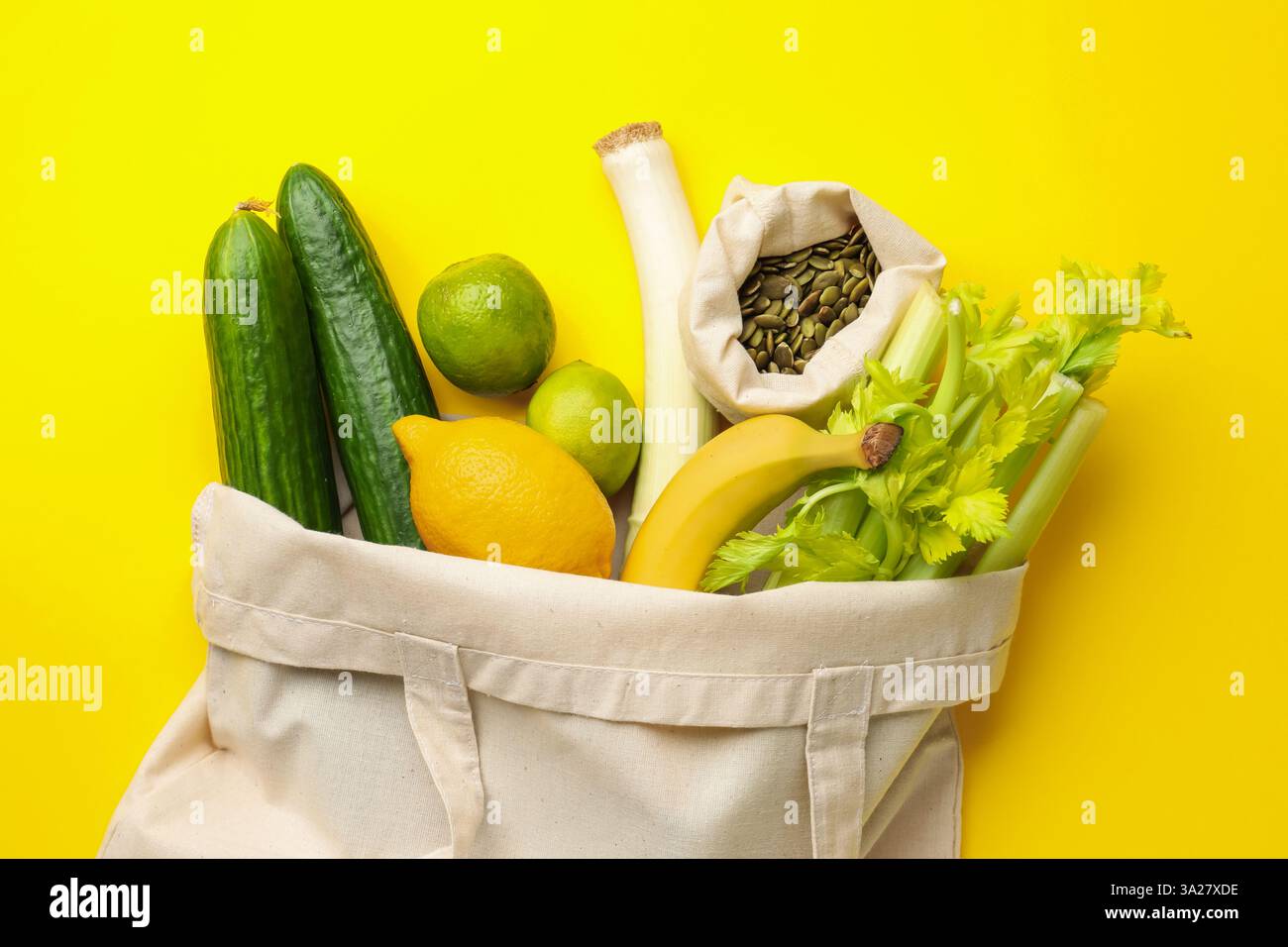 Sac écologique avec des légumes, des fruits et des graines de citrouille sur fond jaune, vue de dessus Banque D'Images