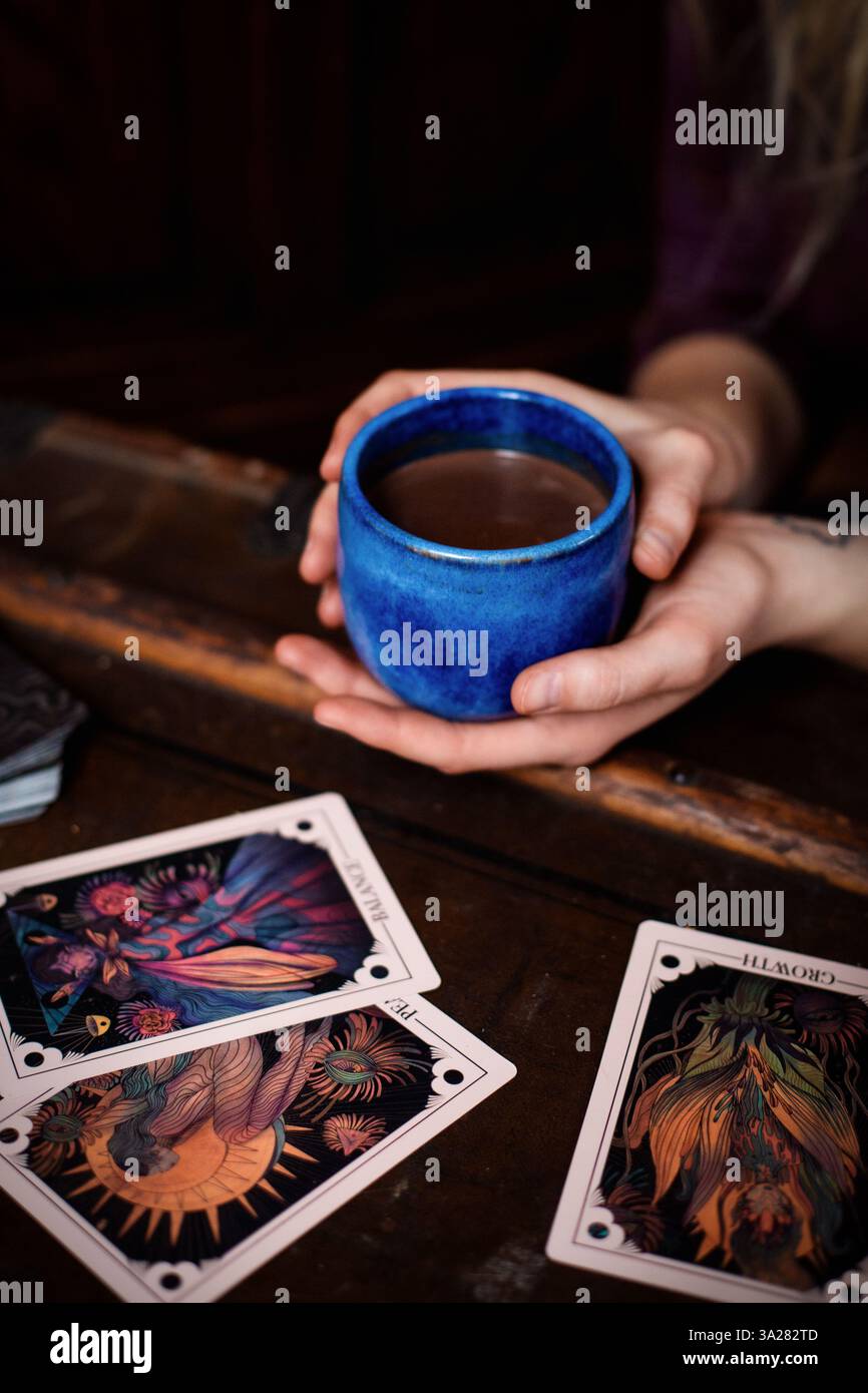Femme tenant la coupe de cacao cérémonielle pendant le rituel spirituel de cacao avec des cartes oracle Banque D'Images