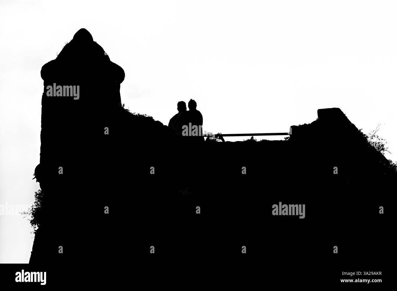 Silhouette de deux personnes posant ensemble pour une photographie sur les murs d'une ancienne forteresse. Noir et blanc. Banque D'Images