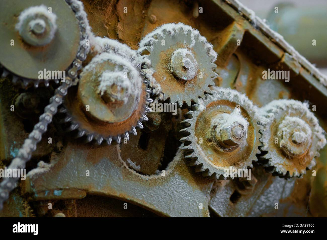 Détails complexes de machines textiles vintage mettant en valeur des engrenages et des chaînes usés dans un environnement industriel abandonné Banque D'Images