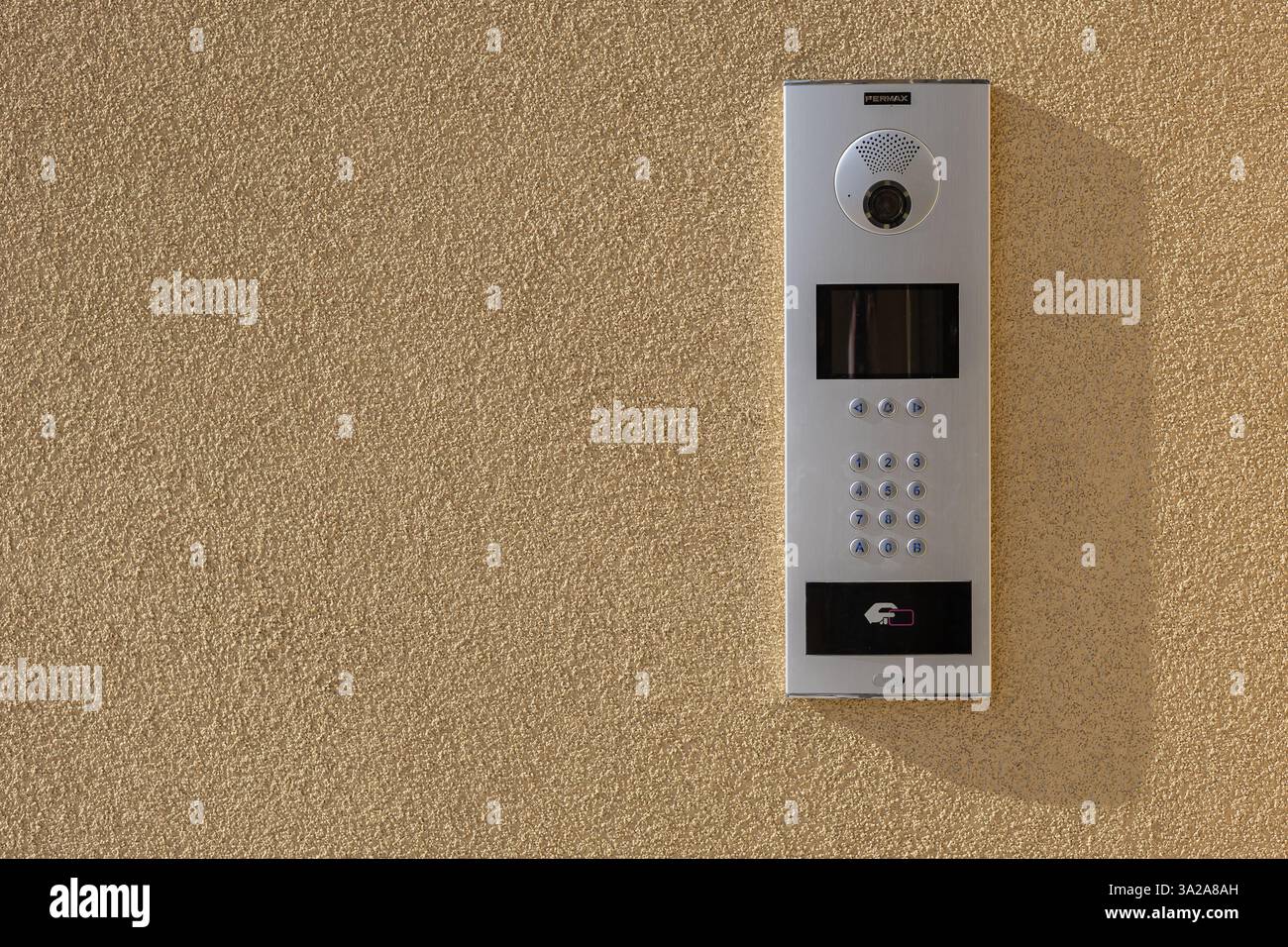 Système d'interphone moderne avec caméra, clavier et accès RFID sur mur texturé à la lumière du soleil. Technologie de sécurité pour bâtiments résidentiels et commerciaux Banque D'Images