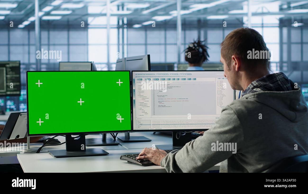 Développeur de logiciels utilisant un PC à écran vert pour faire de la programmation dans la salle des serveurs fournissant des ressources informatiques pour les charges de travail. Expert EN INFORMATIQUE supercalculateurs de centres de données à l'aide d'un ordinateur maquette, d'une caméra A. Banque D'Images