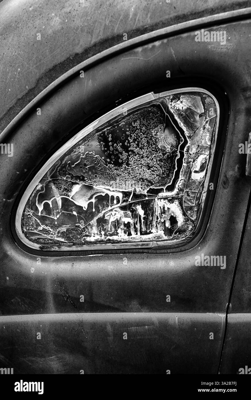 Une lunette arrière d'une voiture rouillée est embuée avec une certaine forme de corrosion. En noir et blanc. Banque D'Images