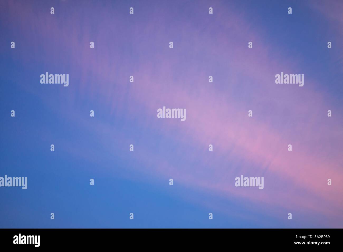 Alors que le crépuscule s'installe, de doux nuages roses s'étendent sur un ciel clair, créant une atmosphère sereine. Les teintes de rose et de bleu se mélangent magnifiquement, signalant Banque D'Images