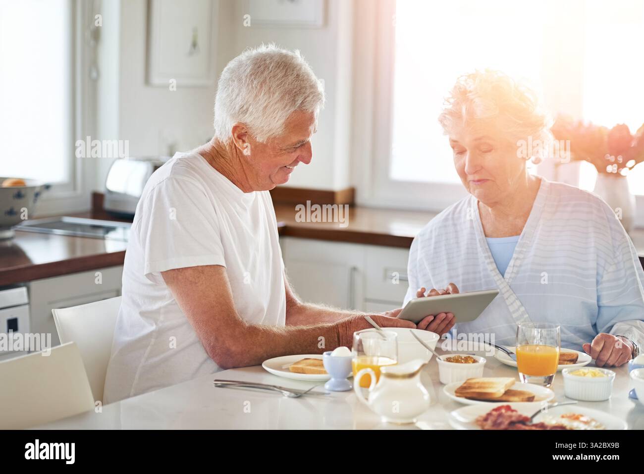 Couple senior, tablette et manger de la nourriture dans la cuisine sur les médias sociaux, lire blog et recherche sur Internet. Personnes âgées, digital ou liaison du petit déjeuner Banque D'Images