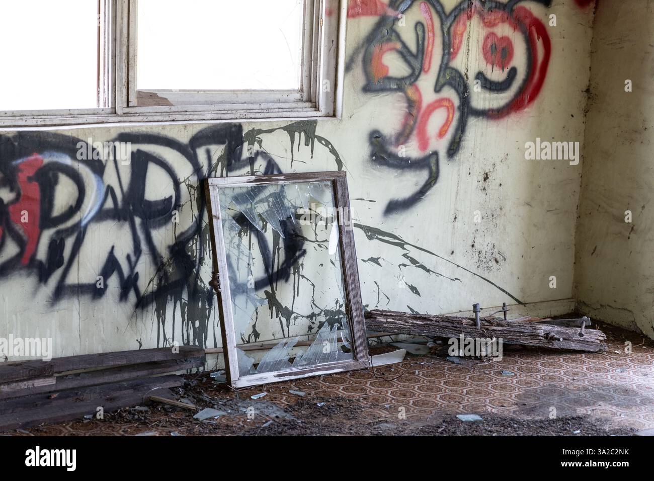 Fenêtre cassée sur le sol d'une pièce graffinée dans une maison abandonnée Banque D'Images