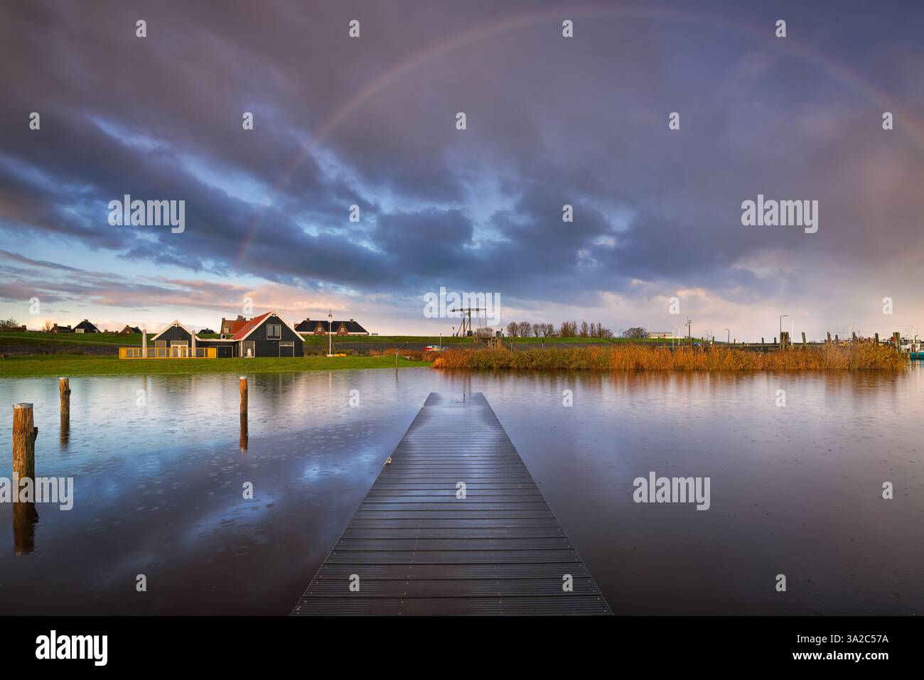 Un reflet parfait des nuages orageux dans le lac Lauwersmeer aux pays-Bas avec un quai menant à l'horizon. Banque D'Images