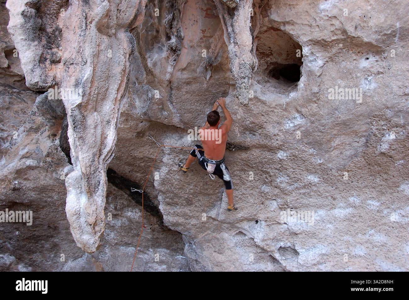 Un grimpeur escaladant les falaises de calcaire escarpées de Phra Nang Beach, en Thaïlande, présentant les célèbres formations surplombantes de la région Banque D'Images