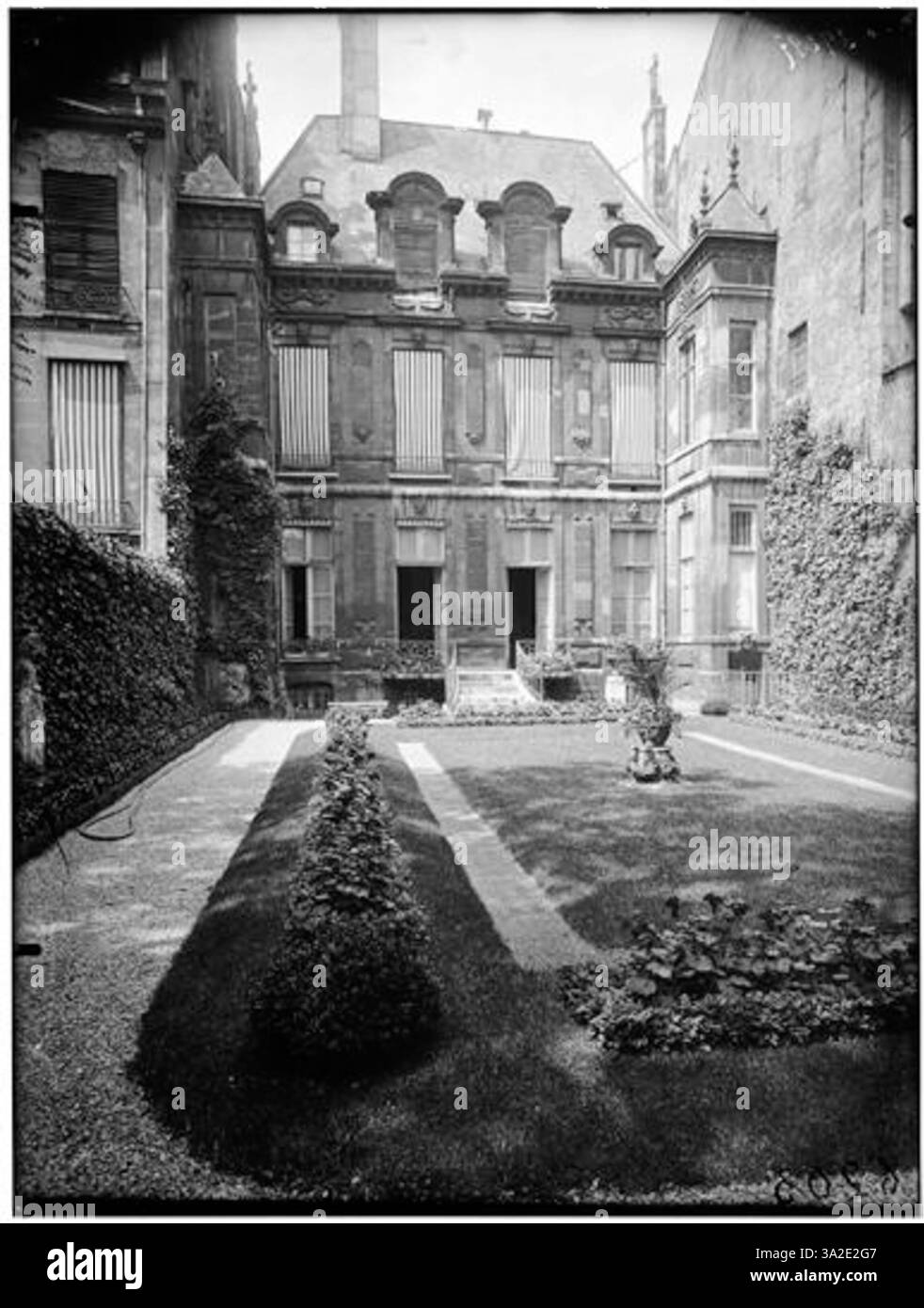 Cette photographie de 1910 d'Eugène Atget montre une façade donnant sur un jardin, reflétant l'architecture et les styles paysagers du Paris du début du XXe siècle. Banque D'Images