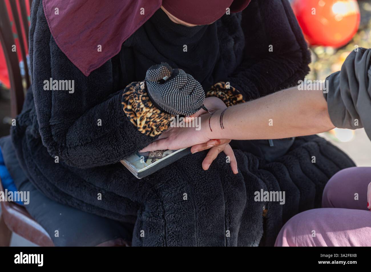 Un artiste qualifié de henné applique des dessins complexes sur la main d'un client à Marrakech. Banque D'Images